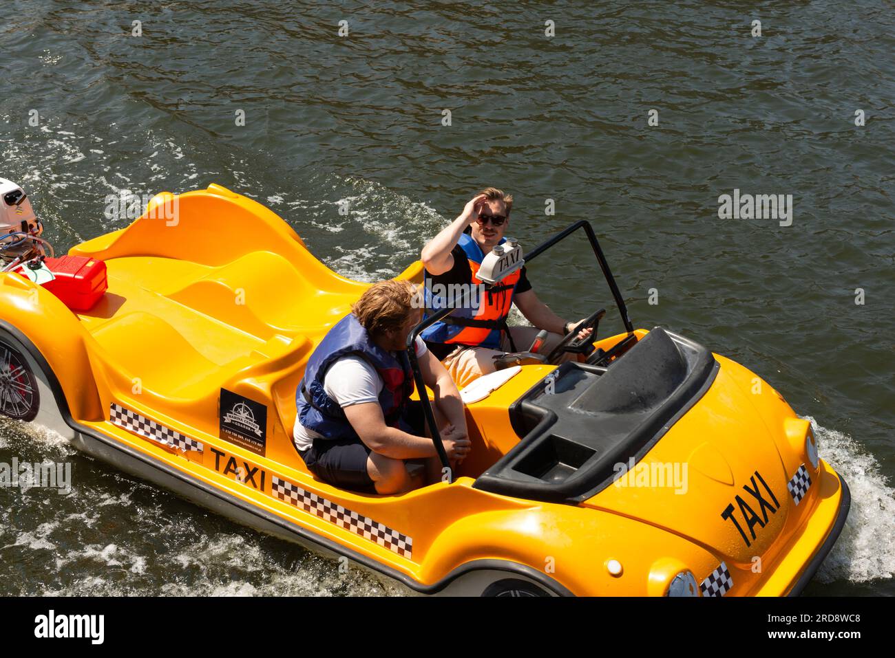 Male tourists in small yellow motorboat taxi on the Motlawa River in the Old Town of Gdansk, Poland Stock Photo