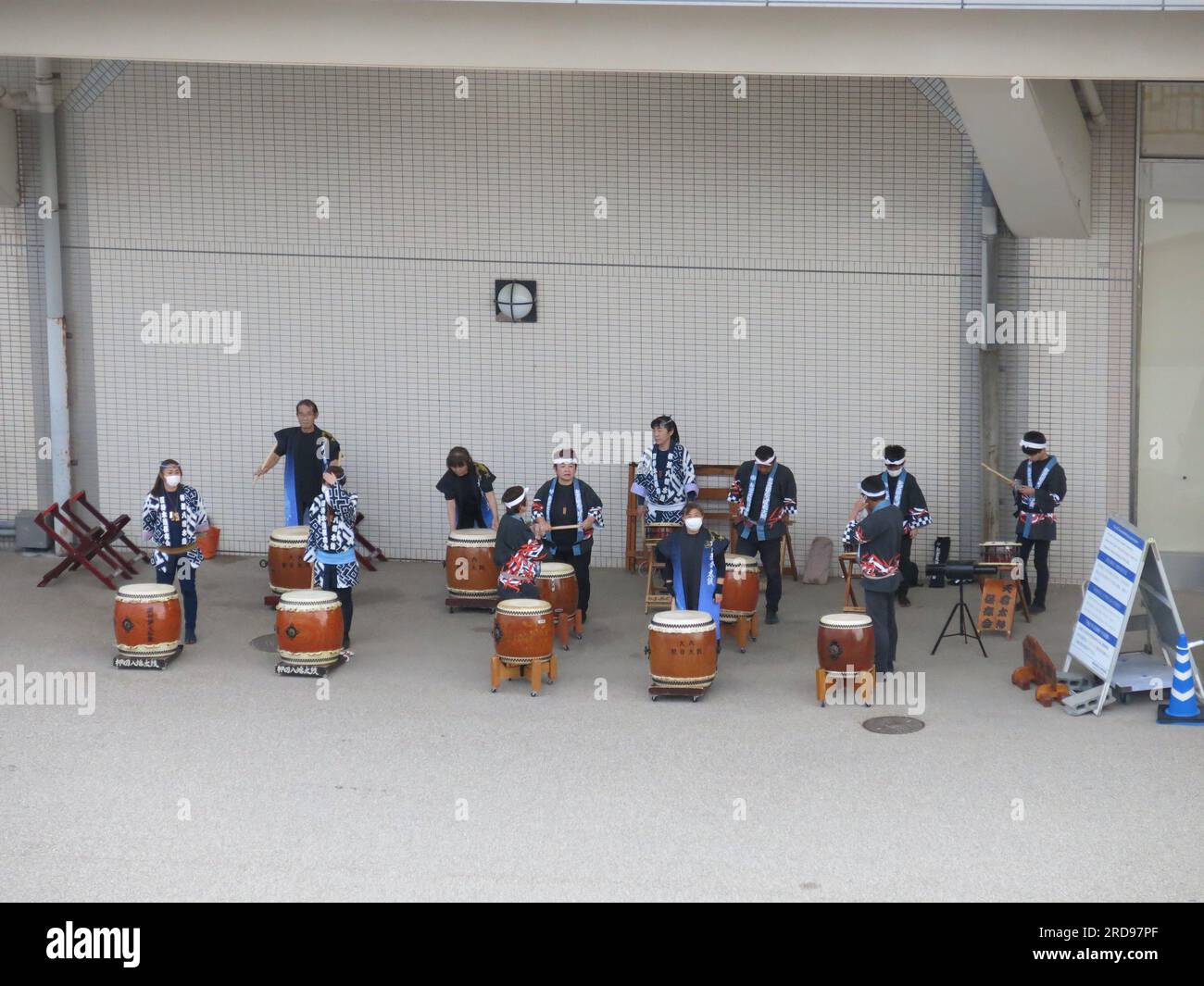 A group of Japanese drummers in traditional costume play their drums on