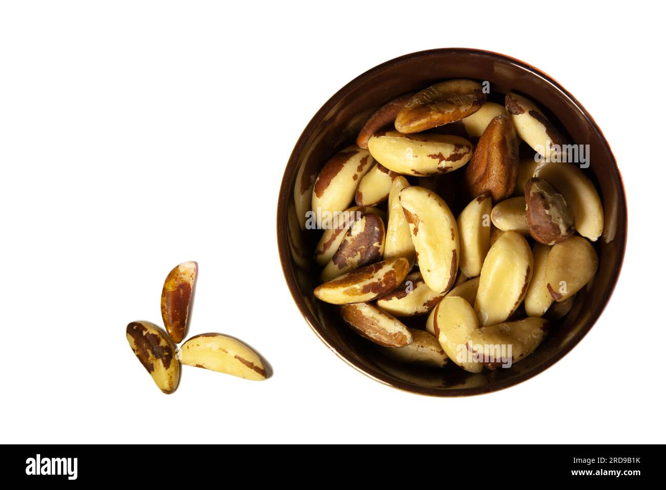 Brazil nuts in a dark ceramic bowl on a white background. Top view. Stock Photo