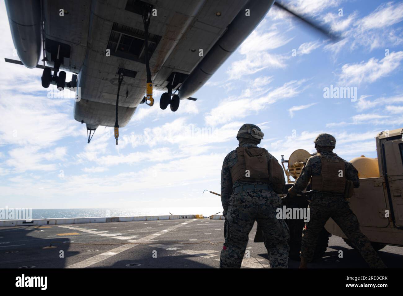 U.S. Marines with Combat Logistics Battalion 31, 31st Marine Expeditionary Unit, prepare to attach supplies to CH-53E Super Stallion during a real-life helicopter support team  aboard the amphibious transport dock ship USS Green Bay (LPD-20) in the Coral Sea, July 1, 2023. The HST was in support of establishing a forward arming and refueling point for real-life training and sustainment. The 31st MEU is operating aboard ships of the America Amphibious Ready Group in the 7th Fleet area of operations to enhance interoperability with allies and partners and serve as a ready response force to defen Stock Photo