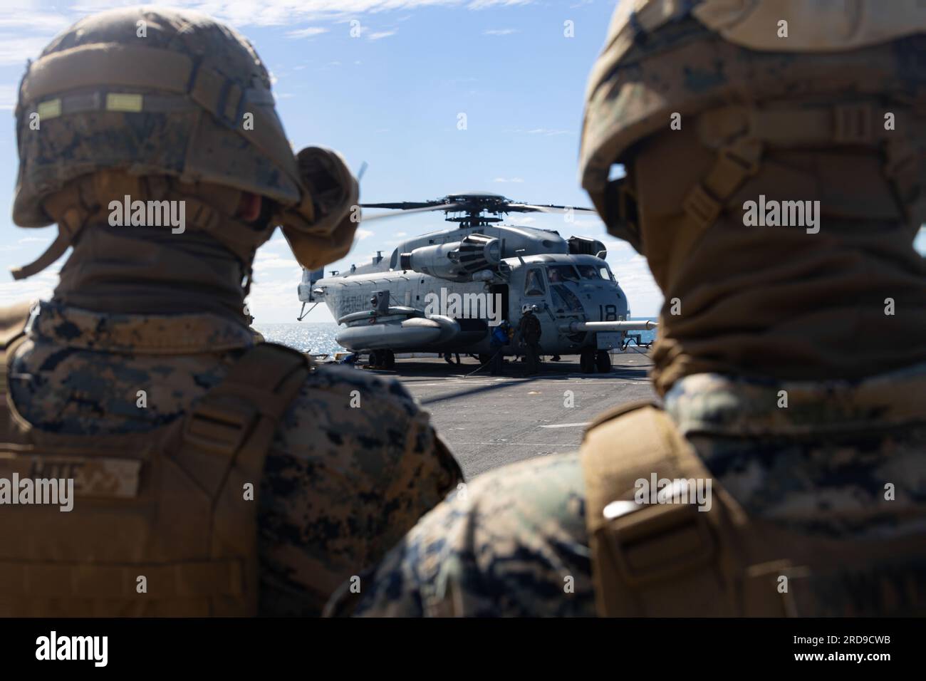 U.S. Marines with Combat Logistics Battalion 31, 31st Marine Expeditionary Unit, observe a CH-53E Super Stallion during a real-life helicopter support team  aboard the amphibious transport dock ship USS Green Bay (LPD-20) in the Coral Sea, July 1, 2023. The HST was in support of establishing a forward arming and refueling point for real-life training and sustainment. The 31st MEU is operating aboard ships of the America Amphibious Ready Group in the 7th Fleet area of operations to enhance interoperability with allies and partners and serve as a ready response force to defend peace and stabilit Stock Photo