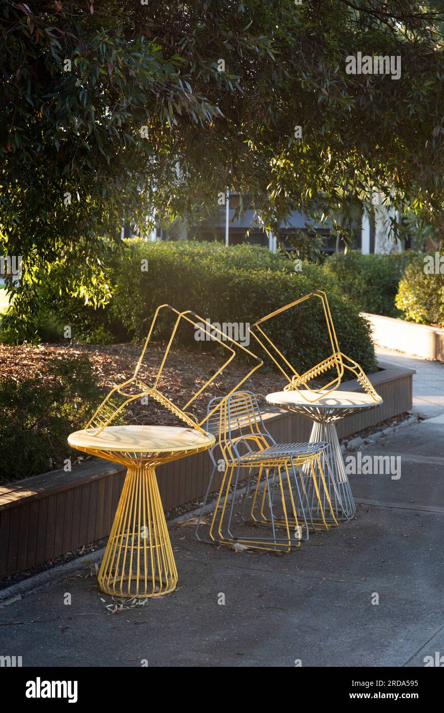Modern outdoor seating in neatly stacked on a table, with a sign indicating the closing time. Stock Photo