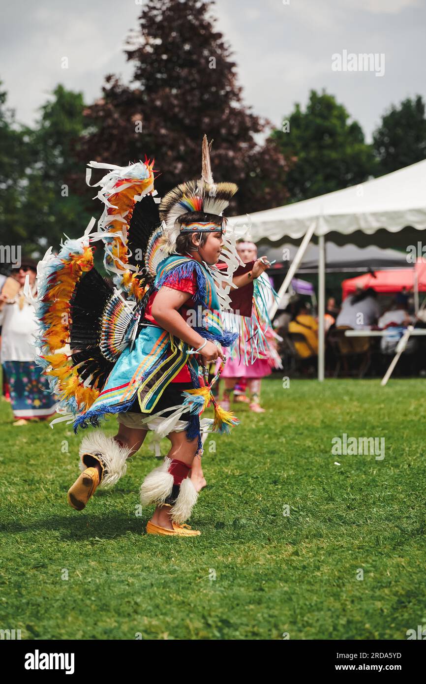 young native American boy dressed in colorful dancing outfit at pow wow event to celebrate indigenous culture Stock Photo