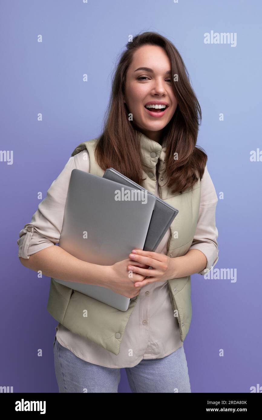 positive 30s lady student holding documents and laptop on empty space background Stock Photo