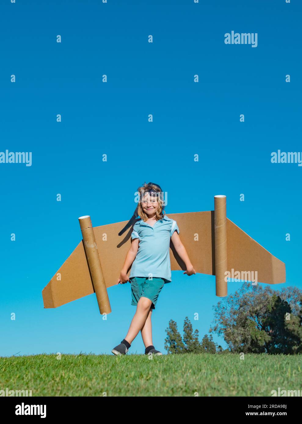 Child boy playing with cardboard toy airplane wings craft in sky with