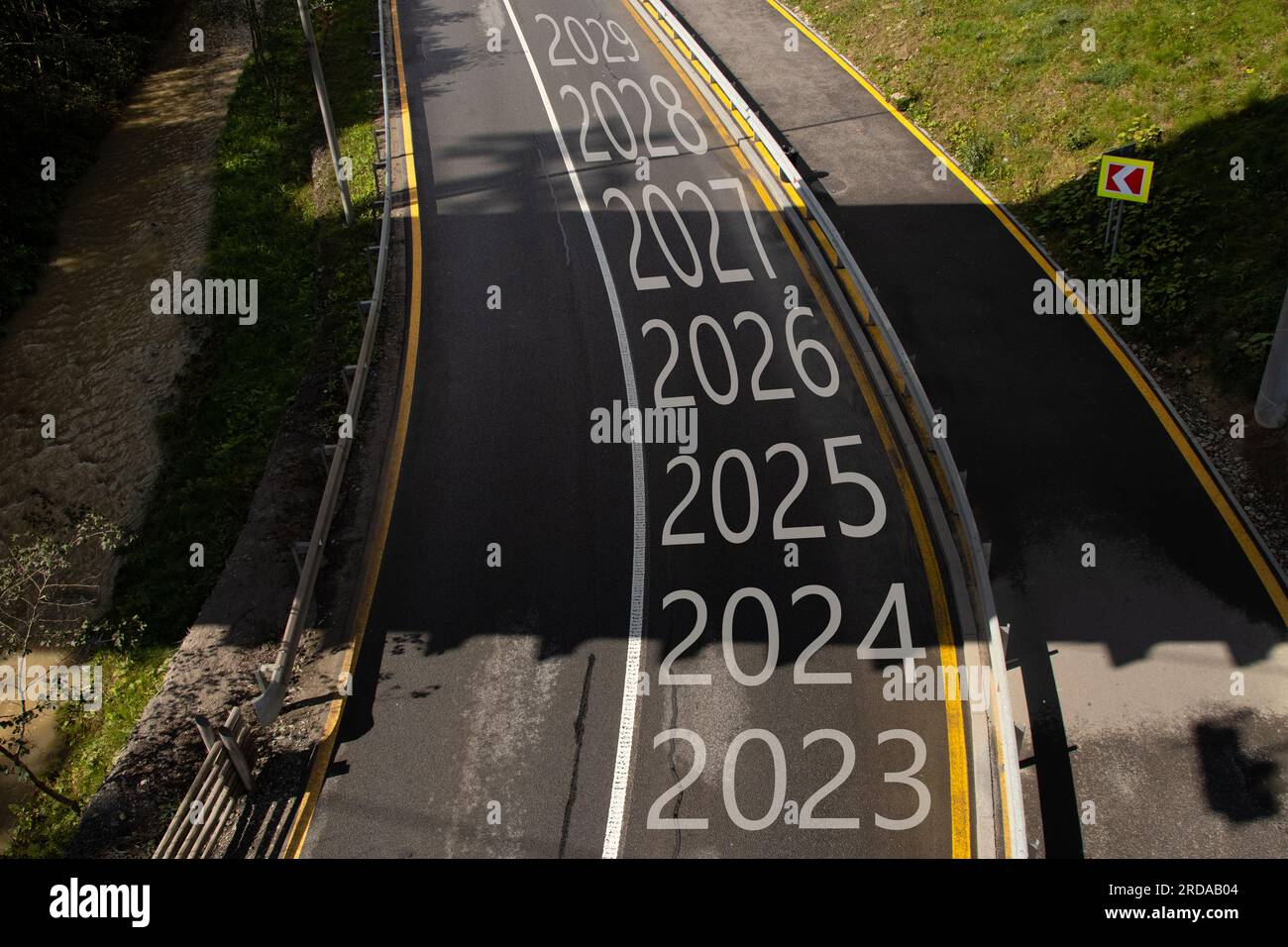The years from 2023 to 2029 are written on the road with a turn to the left, the road goes in the mountains in the Carpathians and along the road ther Stock Photo
