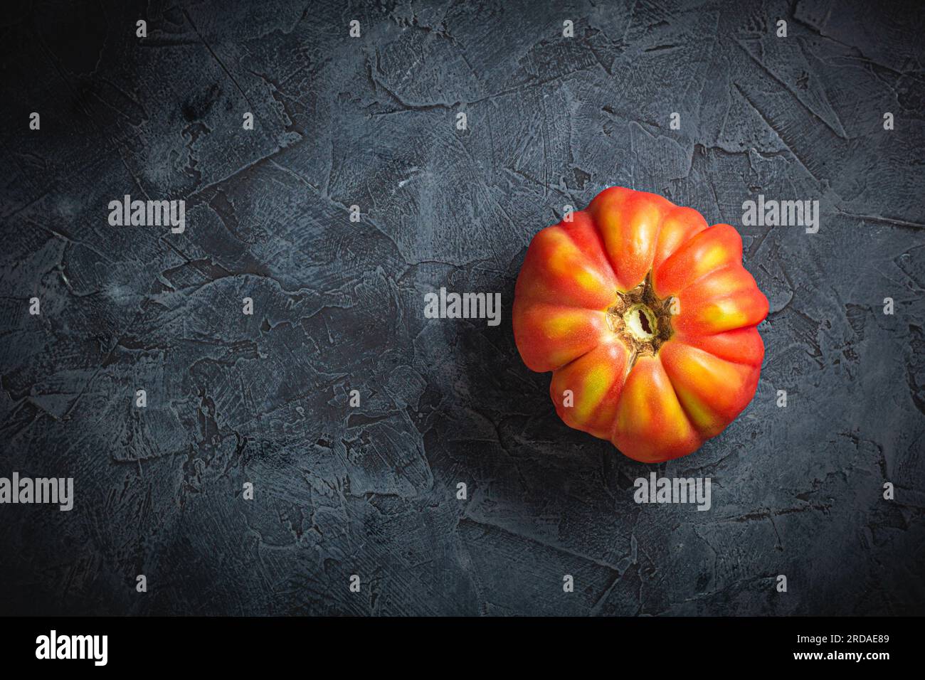 Red ribbed tomato cuore di bue on a dark background top view Stock Photo