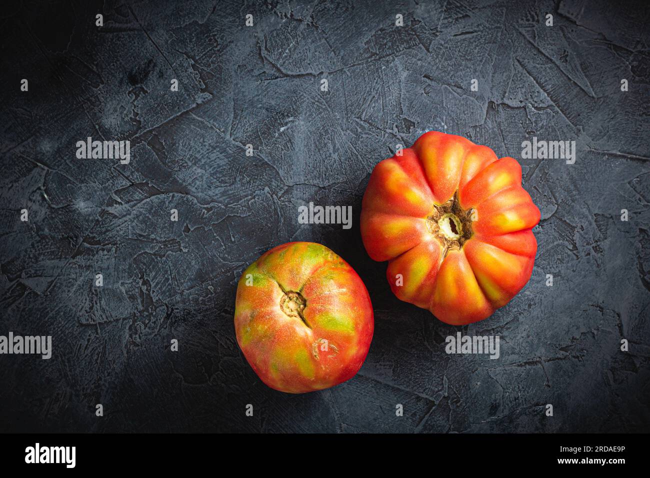 Red ribbed tomato cuore di bue on a dark background top view Stock Photo