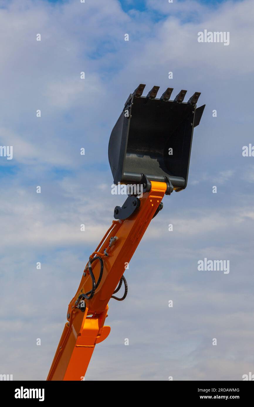 Extended upward lifting arm of an open bucket excavator. Stock Photo