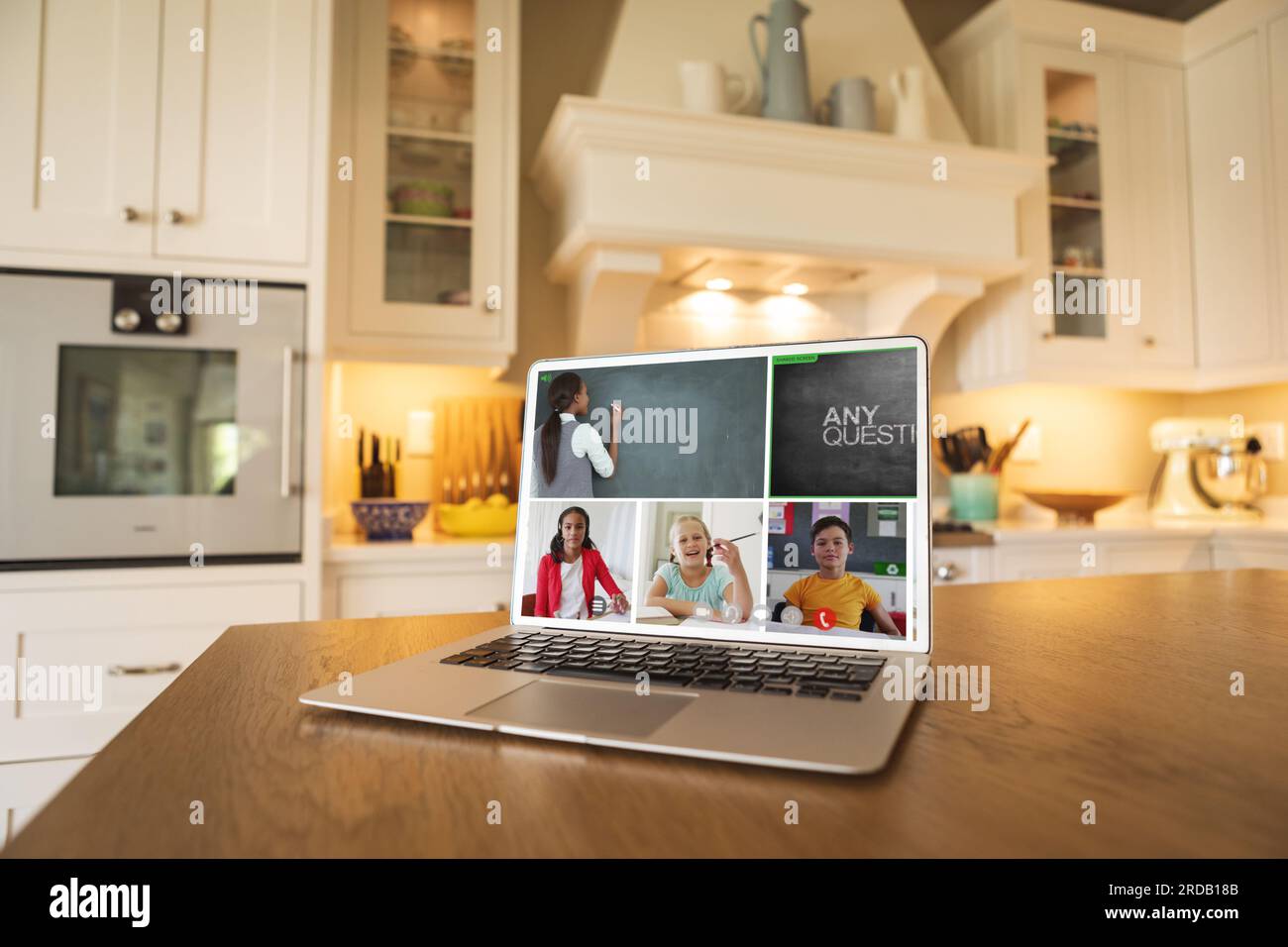 Laptop screen with multiracial teacher and students studying over web conference placed on table Stock Photo