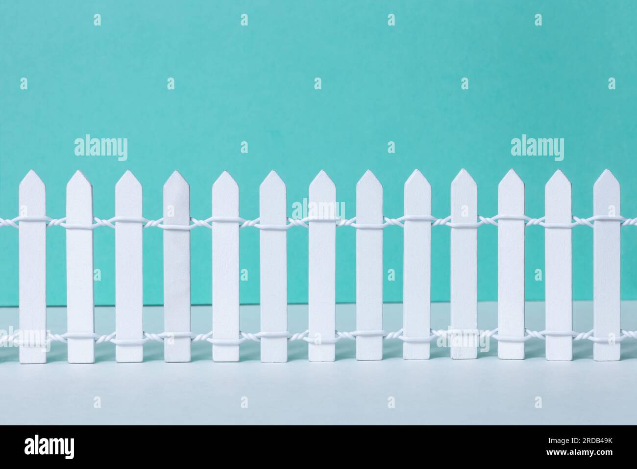 Wooden vintage white picket fence on green background. Small painted