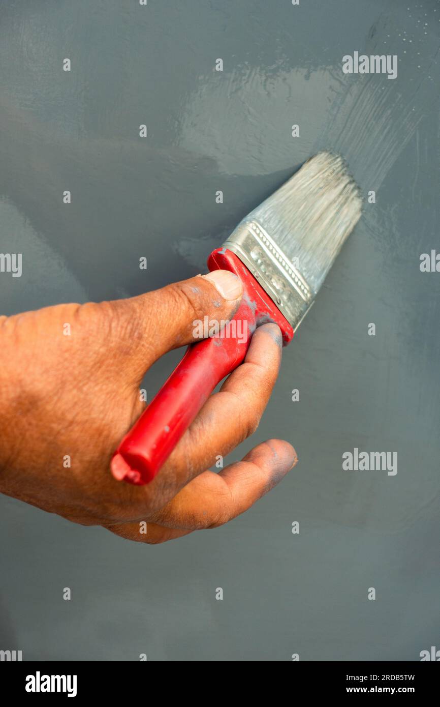 https://c8.alamy.com/comp/2RDB5TW/close-up-shot-of-a-hand-holding-a-re-d-paint-brush-on-a-gray-paint-surface-india-2RDB5TW.jpg