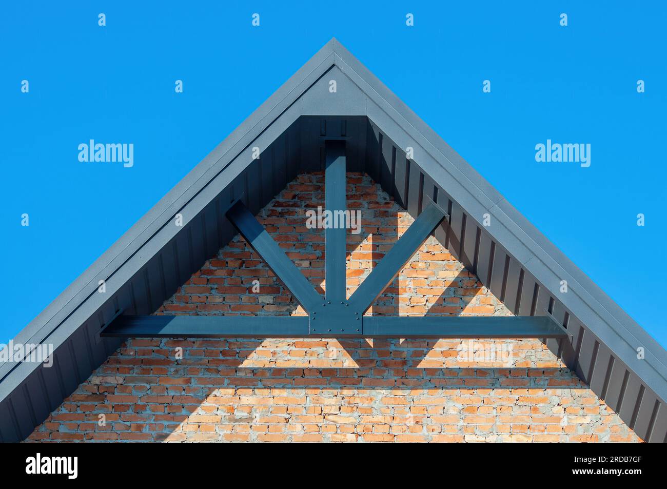 The gable of the house is made of brick and the roof with hemmed soffits, the construction of the roof with decorative beams Stock Photo