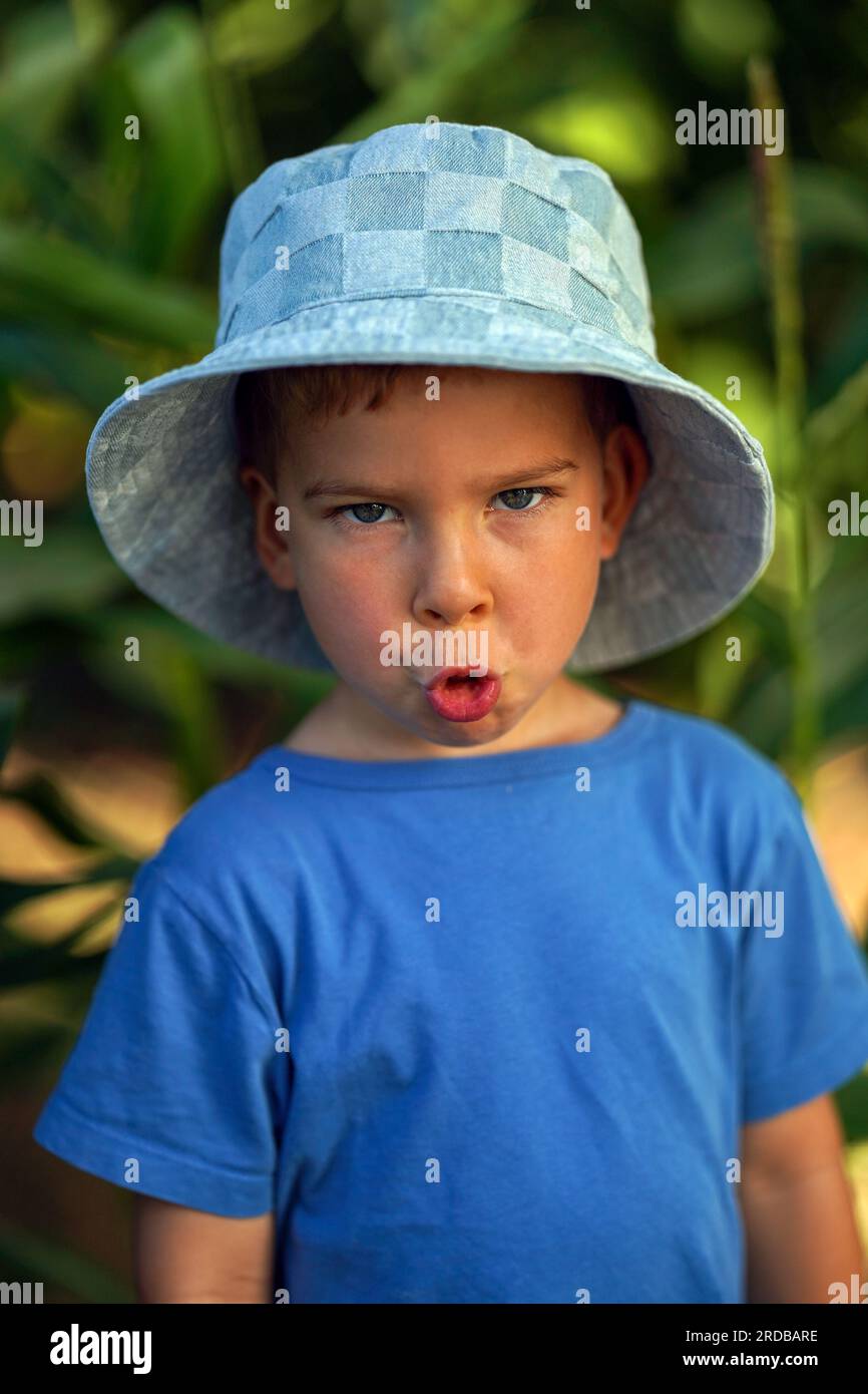 A little boy in summer clothes with a menacing expression on his face