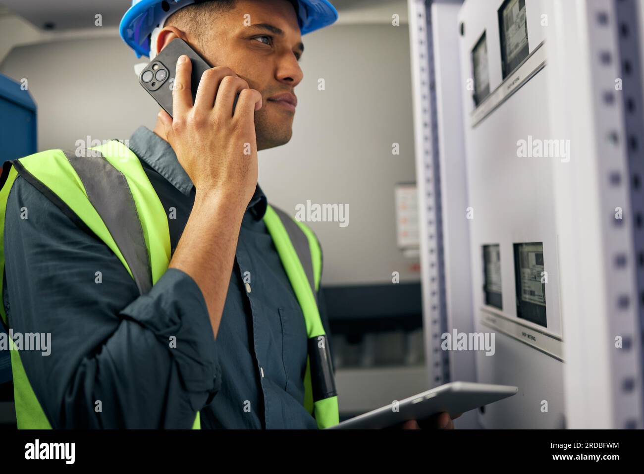 Phone call, man and engineering in control room or technician with switchboard, power box or maintenance on generator. Electrician, construction Stock Photo