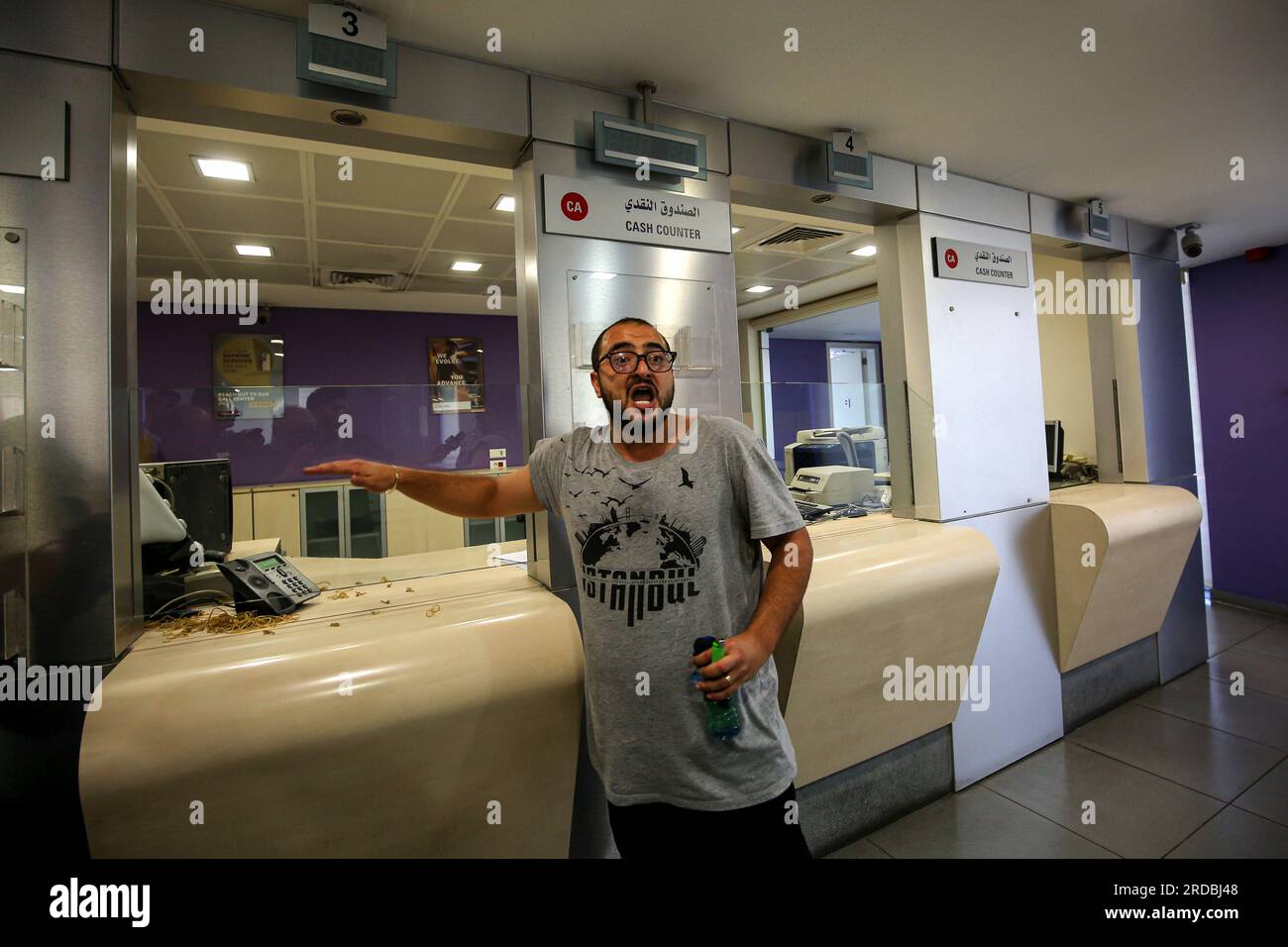Beirut, Lebanon. 20th July, 2023. Lebanese bank depositor Ashraf Salha gestures while holding a plastic bottle of gasoline as he stands outside the cashier counter of a local bank he stormed with Salim Hatoum, demanding to withdraw their trapped savings. The small country's crippling economic crisis has increasingly led to Lebanese depositors deciding to forcefully withdraw their trapped savings, as the country's cash-strapped banks have imposed informal limits on withdrawals. Credit: Marwan Naamani/dpa/Alamy Live News Stock Photo