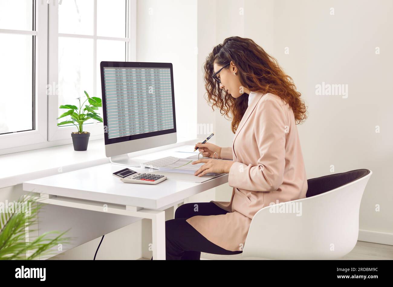 Focused businesswoman analyzing financial spreadsheet report on computer screen Stock Photo