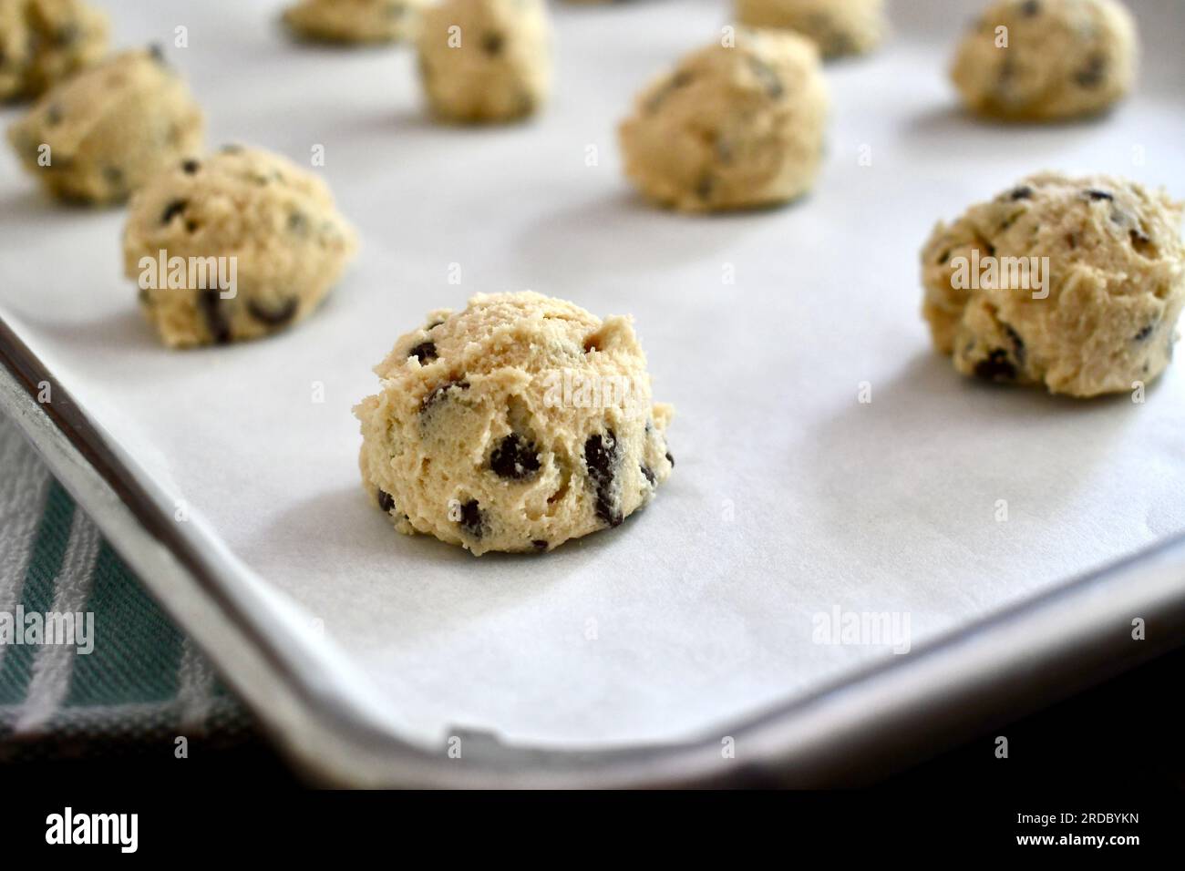 Spoonfuls of chocolate chip cookie dough on a parchment paper lined