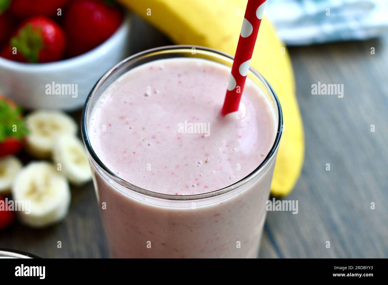 Strawberry banana smoothie in a clear glass on a wooden table Stock Photo