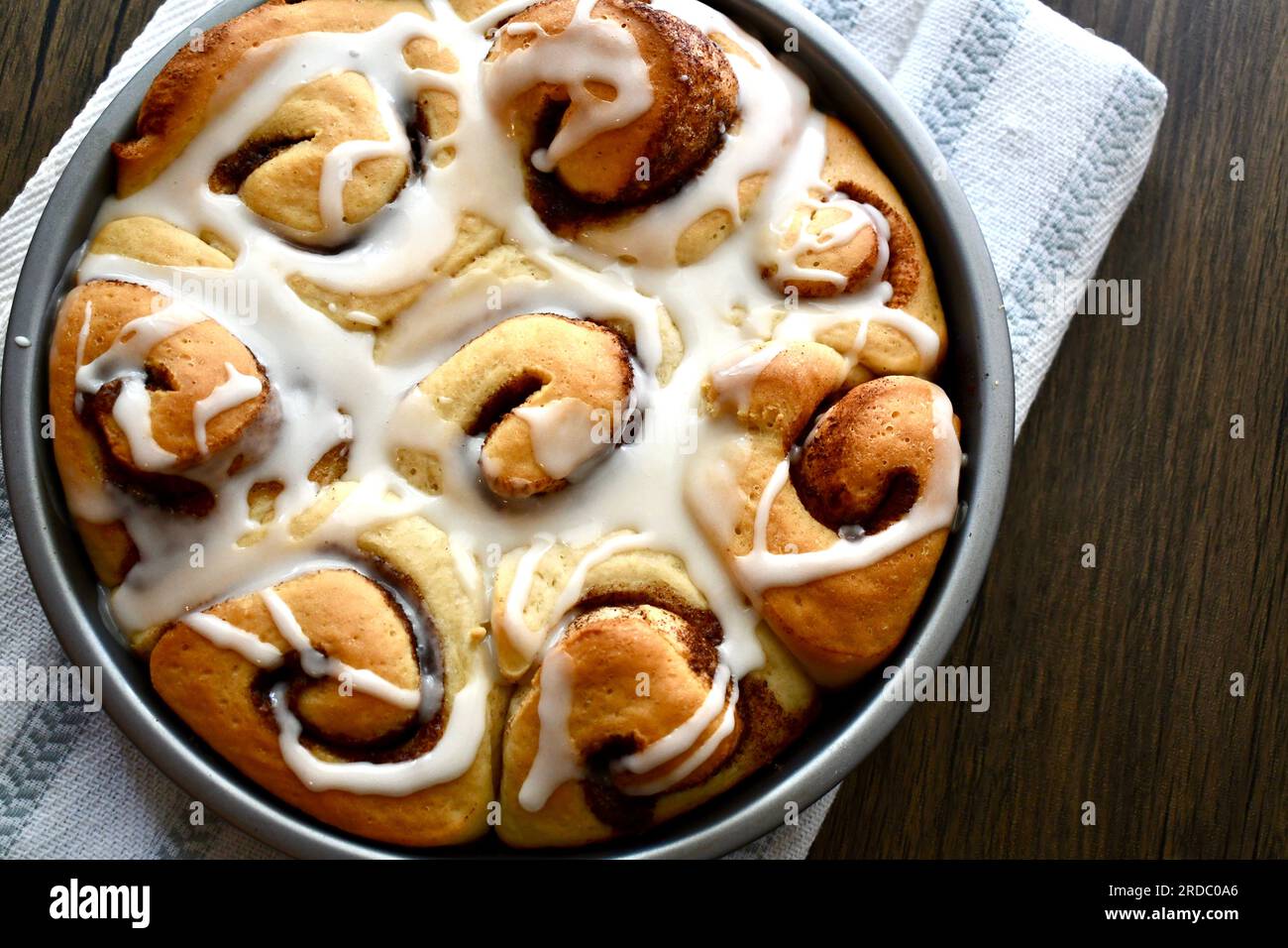 Cinnamon rolls in a round baking pan on a rustic wooden table Stock Photo