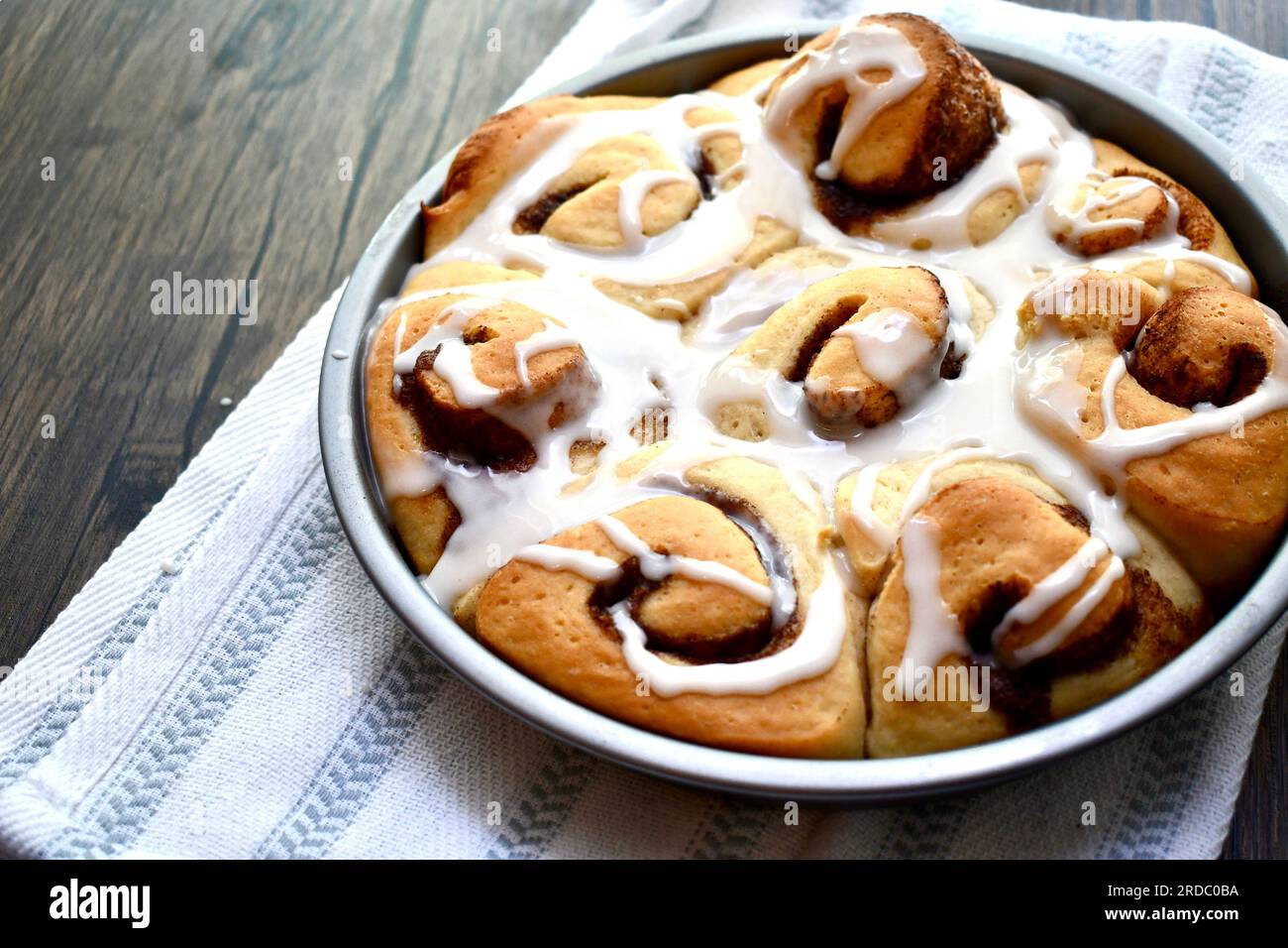 Cinnamon rolls in a round baking pan on a rustic wooden table Stock Photo