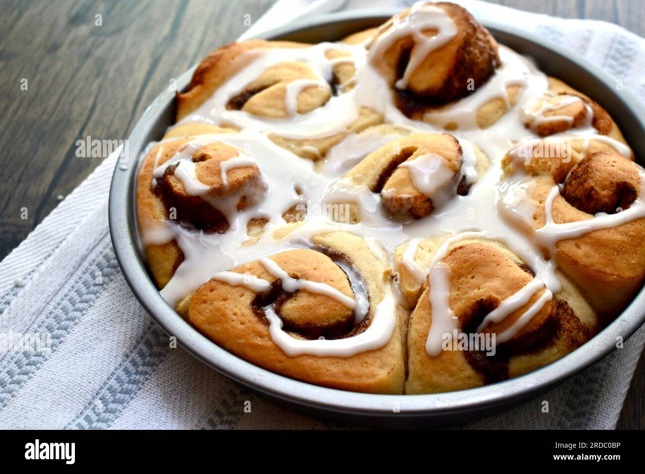 Cinnamon rolls in a round baking pan on a rustic wooden table Stock Photo