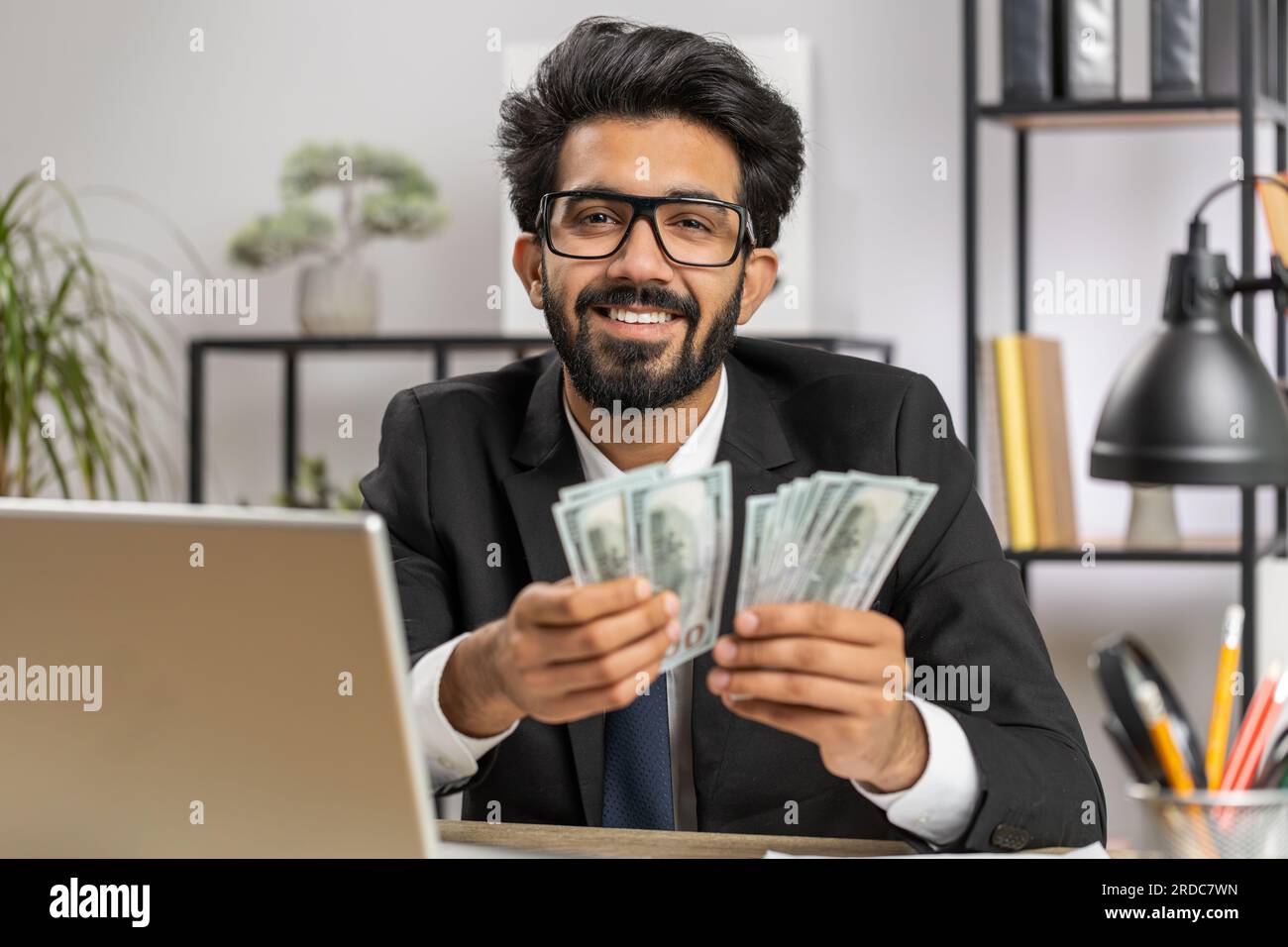Rich indian businessman working on laptop pc counting money cash