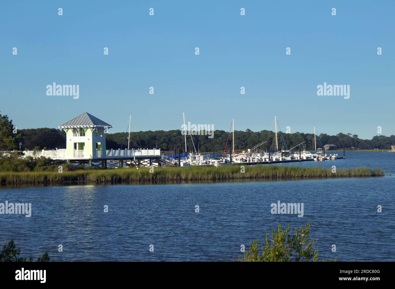 Cape Charles Marina has boats and yachts docked at pier. Evening light darkens water and