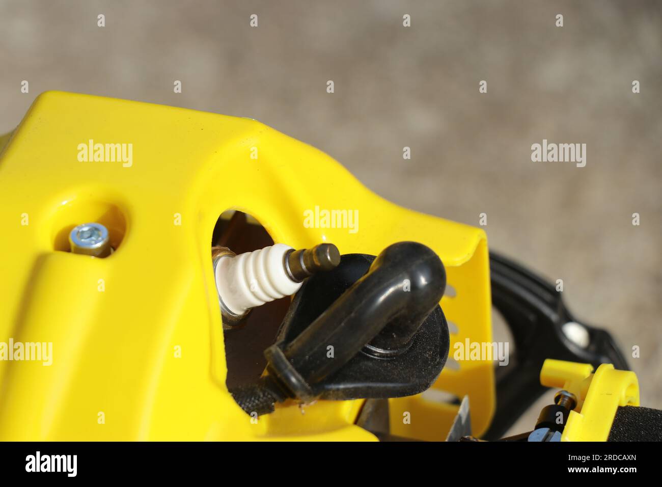 Spark plug in the engine head of a brush cutter machine. Spare parts of a petrol engine Stock Photo