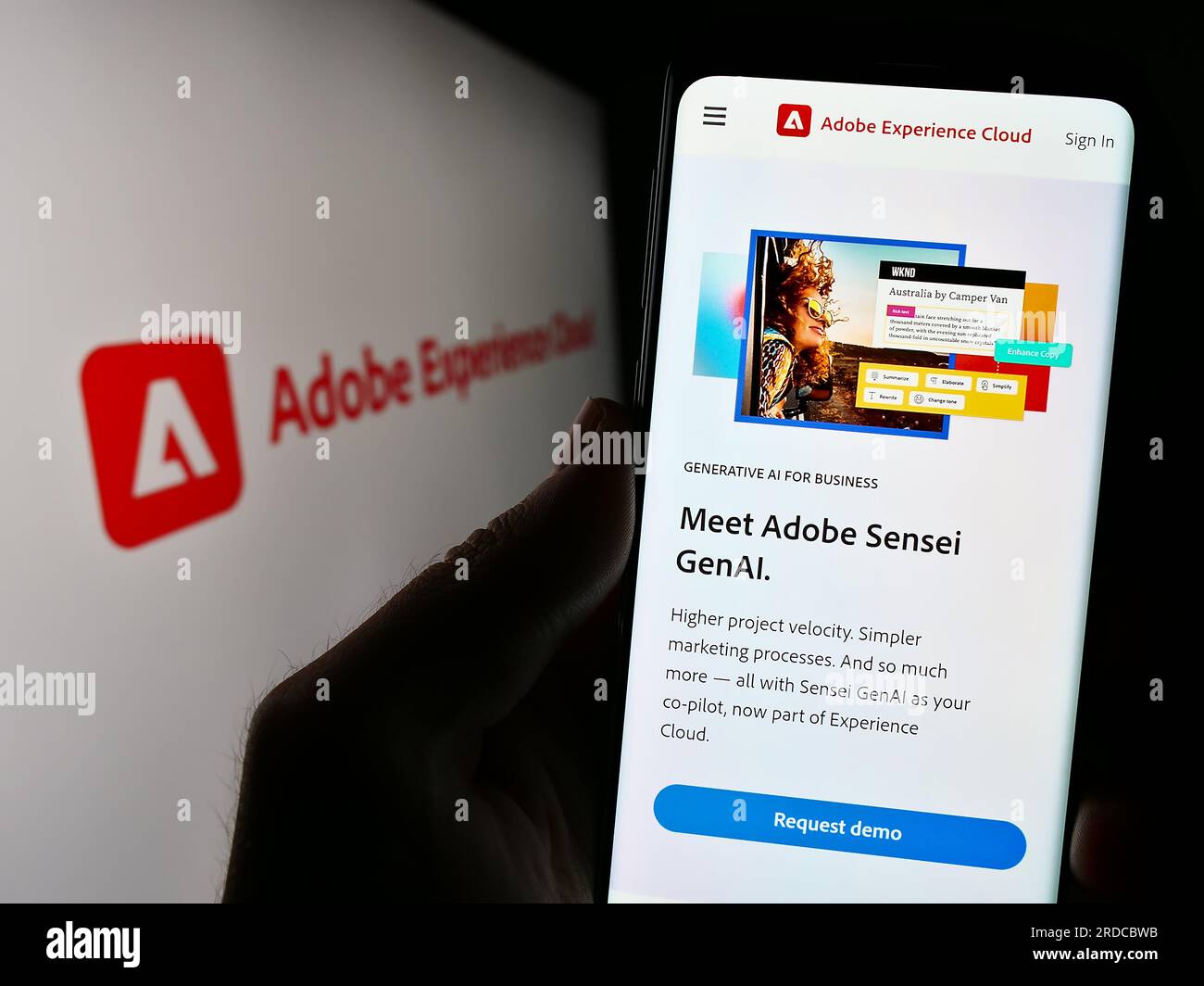 Person holding cellphone with webpage of software product Adobe Experience Cloud (AEC) on screen with logo. Focus on center of phone display. Stock Photo