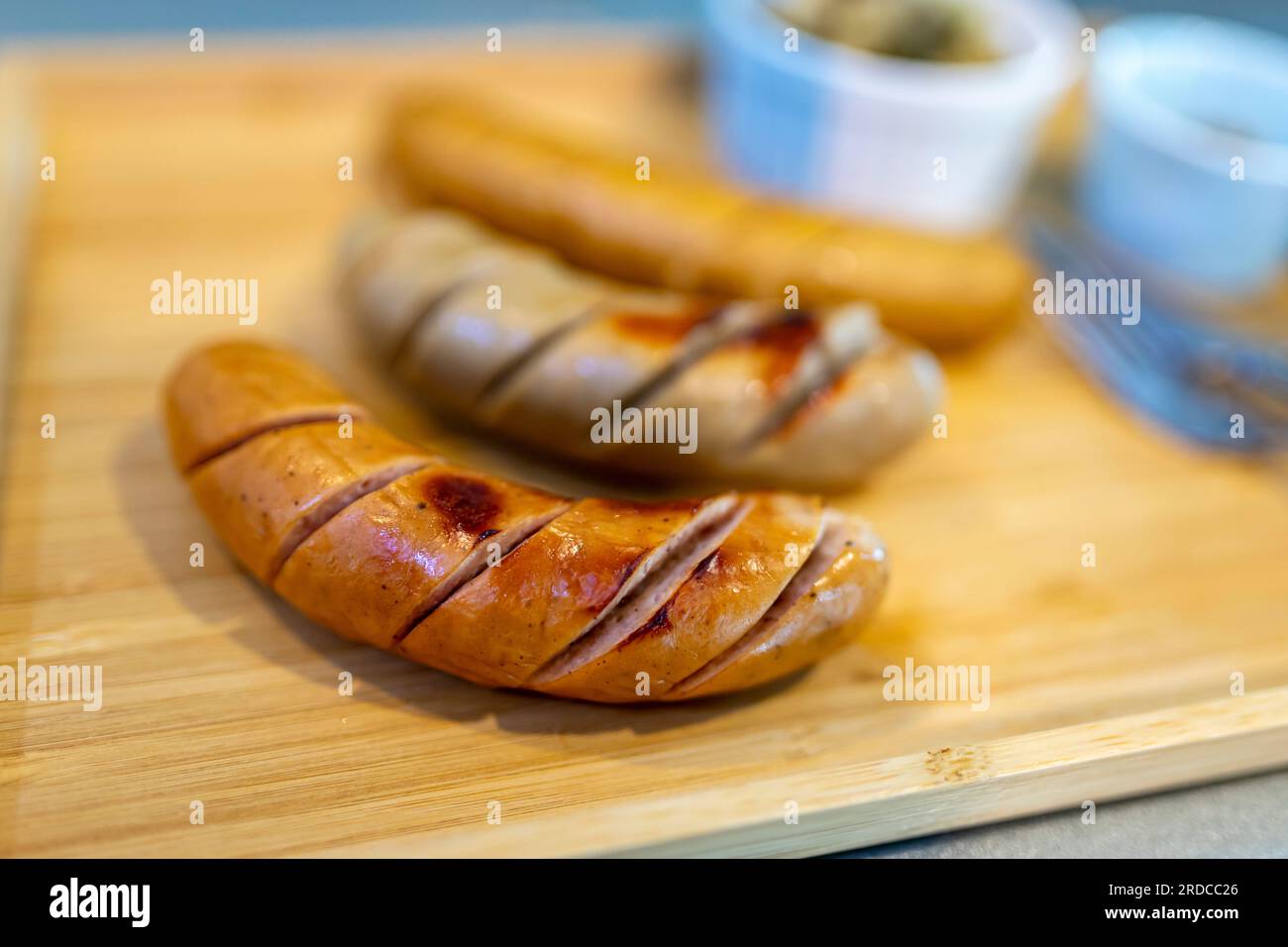close up photo Very shallow focus of grilled German sausages. with sauerkraut and dijon mustard in a small bowl It's a blurred background with copy sp Stock Photo