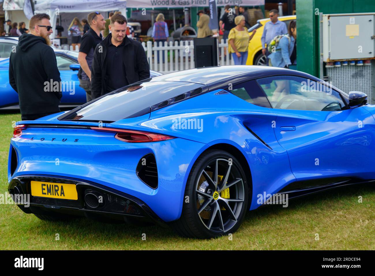 At the Yorkshire Show, there is a gleaming new blue Lotus Emira sportscar on exhibit, which catches the attention of two guys, Harrogate, UK. Stock Photo
