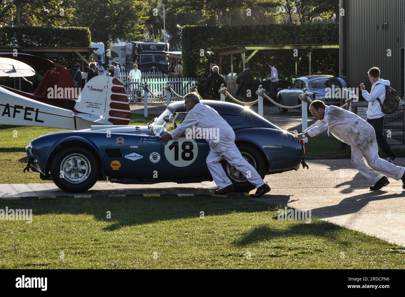 Mechanics pushing a classic AC Cobra 289 racing car out to race early in the morning at the Goodwood Revival 2013. Preparing event Stock Photo