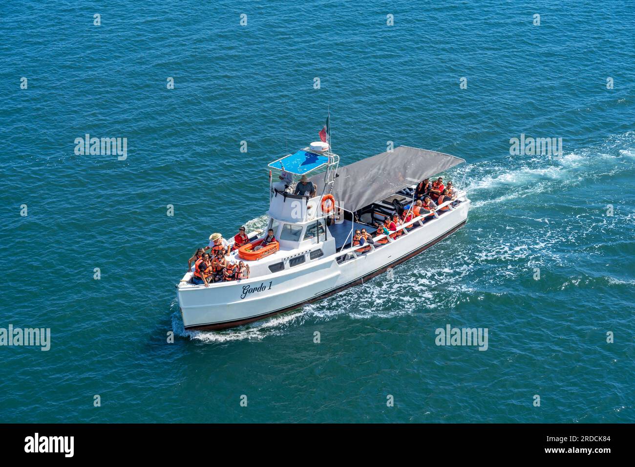 Ensenada, BC, Mexico – June 4, 2023: Tour boat with passengers wearing life jackets on the bay in Ensenada, Mexico. Stock Photo