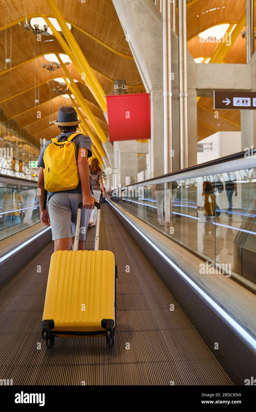 Anonymous traveler with suitcase on travolator Stock Photo