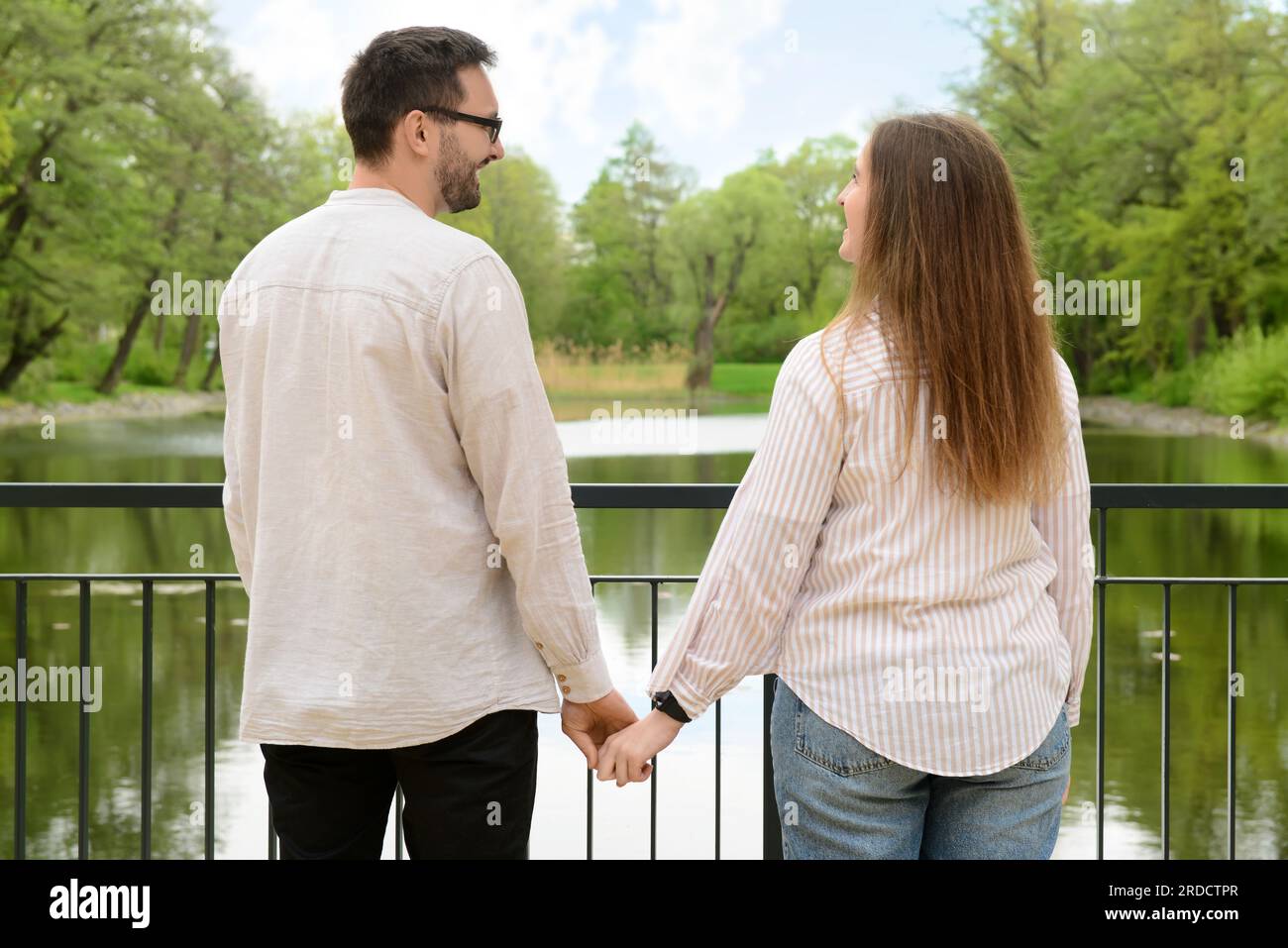 Beautiful loving happy couple holding hands on bridge in park Stock ...