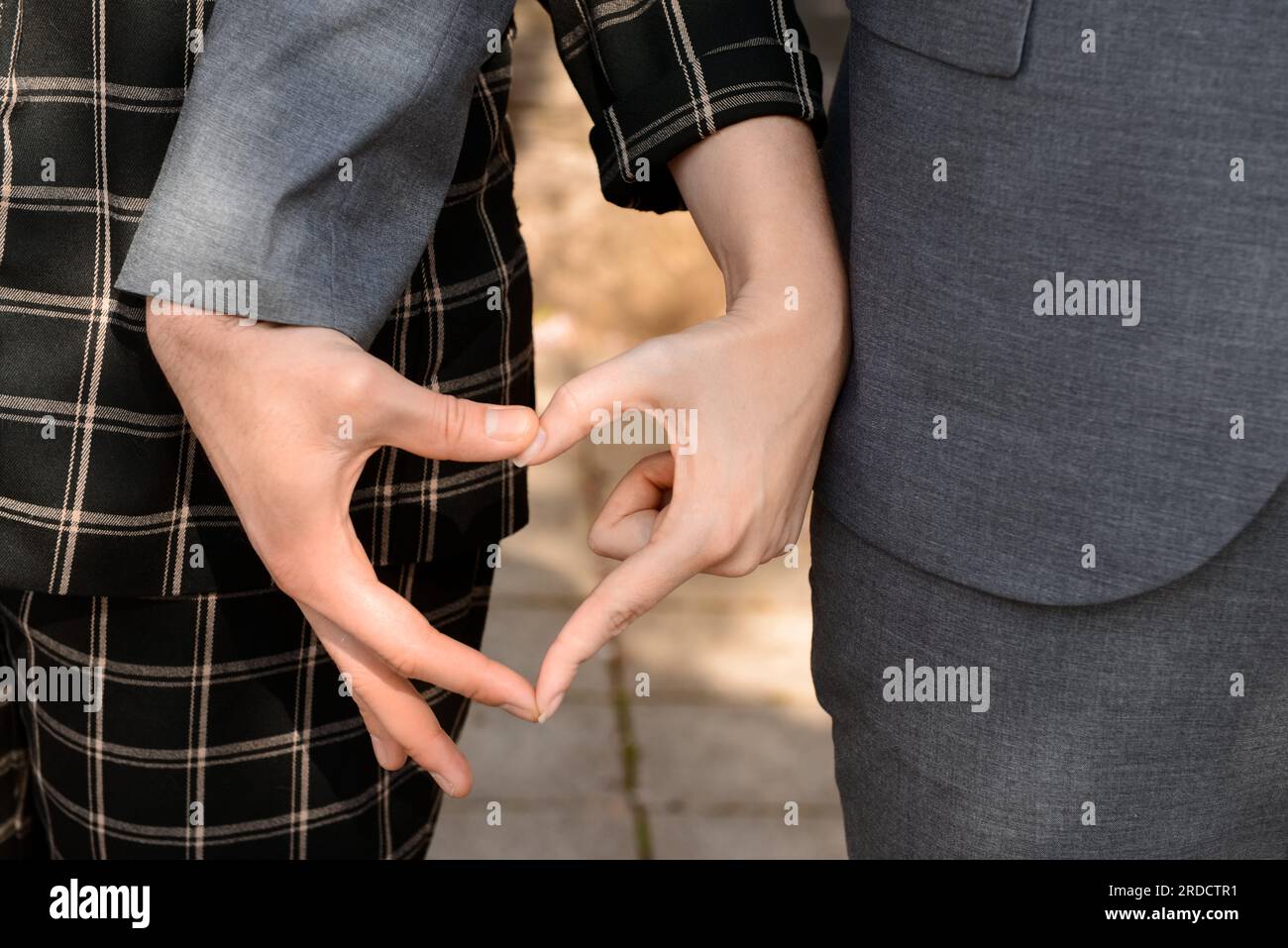 Beautiful couple making heart shape with their hands on sunny spring ...