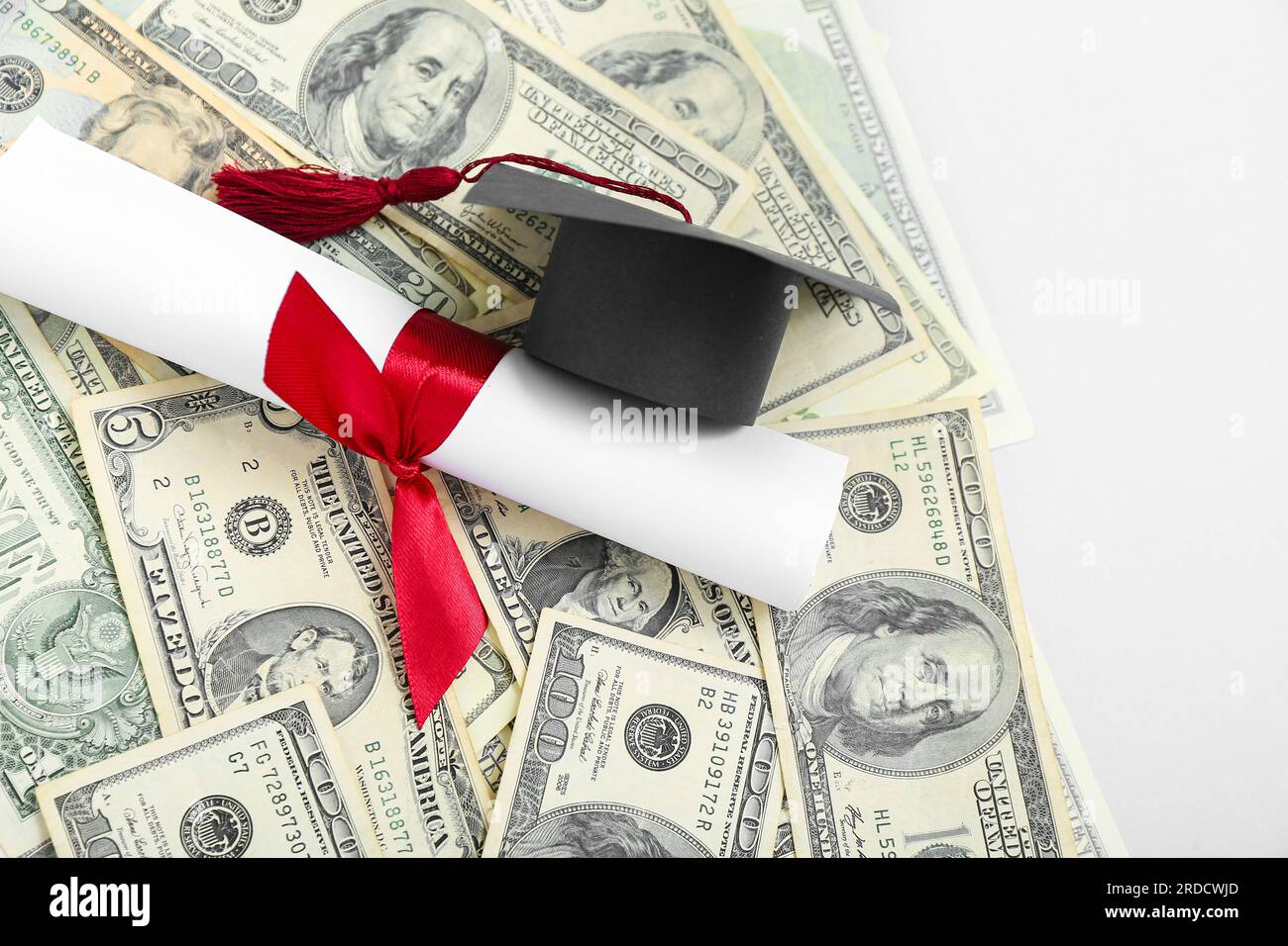 Graduation cap, diploma and dollar banknotes on grey background