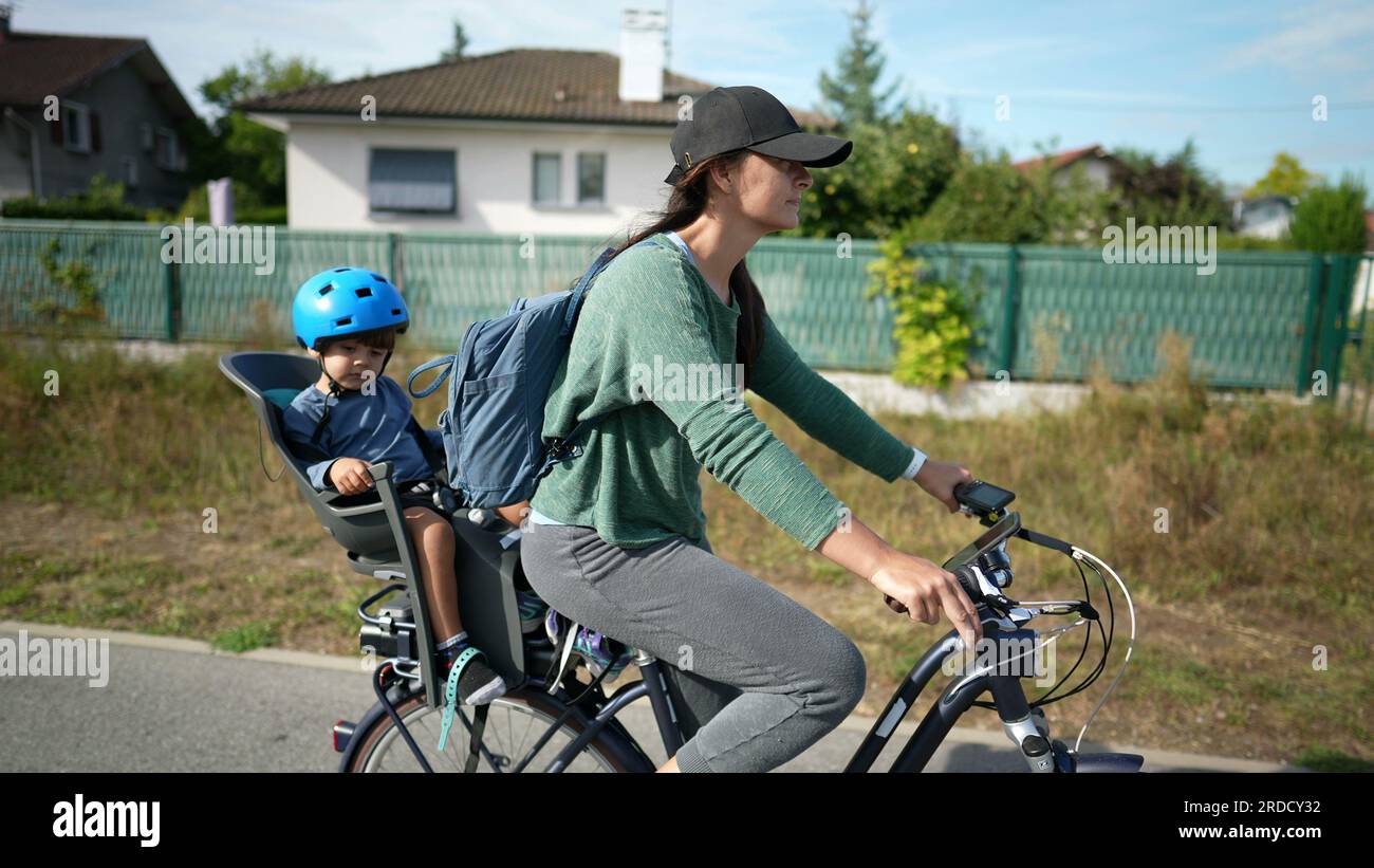 Mother riding bicycle with son in back seat mom rides bike with child Stock Photo Alamy