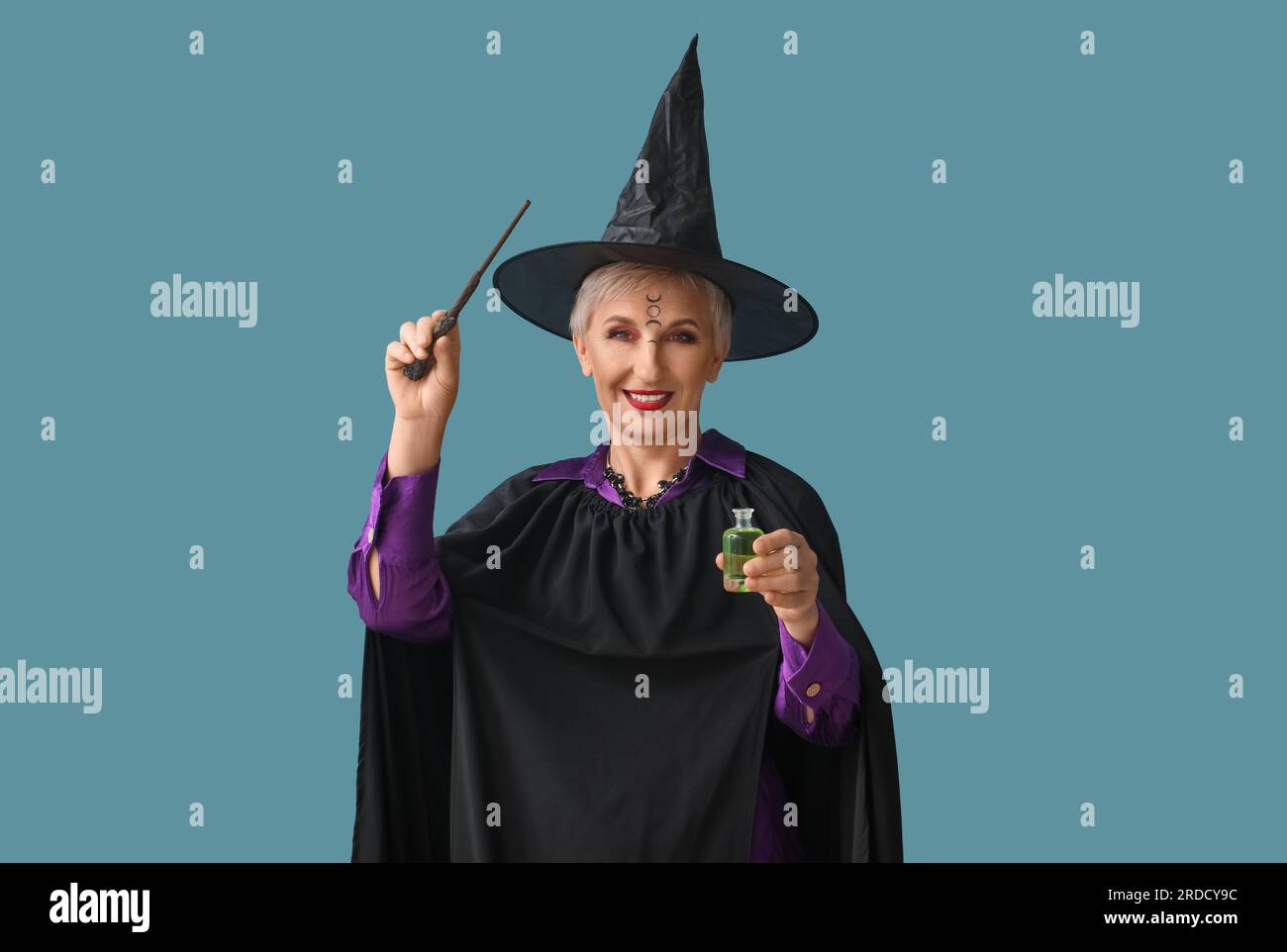 Mature witch with magic wand and poison on blue background Stock Photo ...