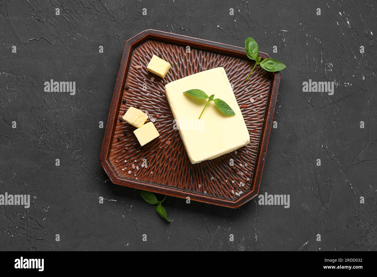 Tray with fresh butter and basil on black background Stock Photo Alamy