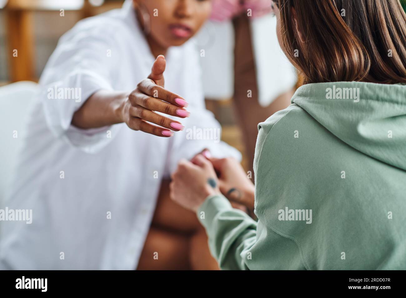 partial view of african american woman outstretching hand while supporting girlfriend during psychological therapy in consulting room, empathy and pro Stock Photo