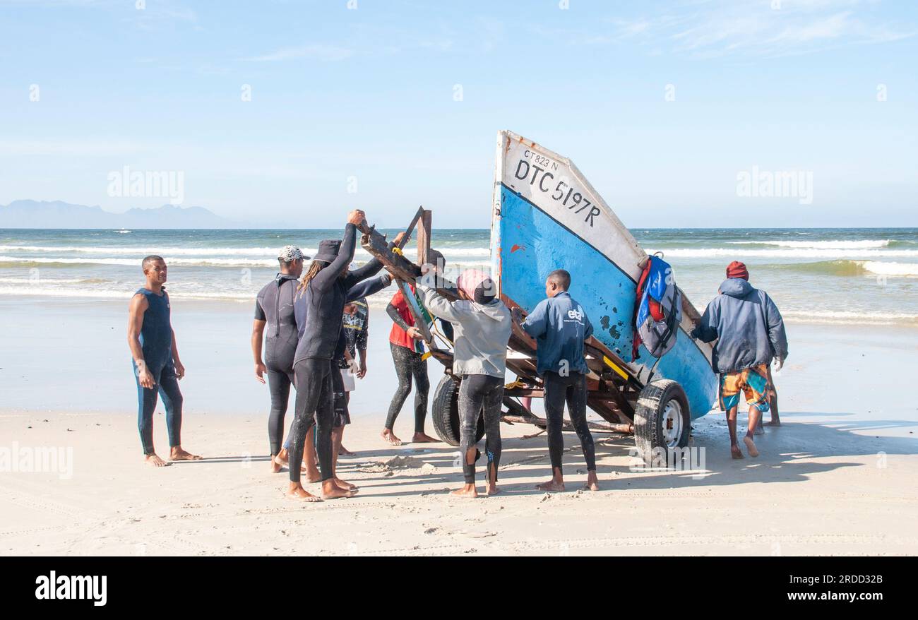 The crew loading a trek fishing boat onto a trailer, at low water. Strandfontein Beach, Western Cape Stock Photo