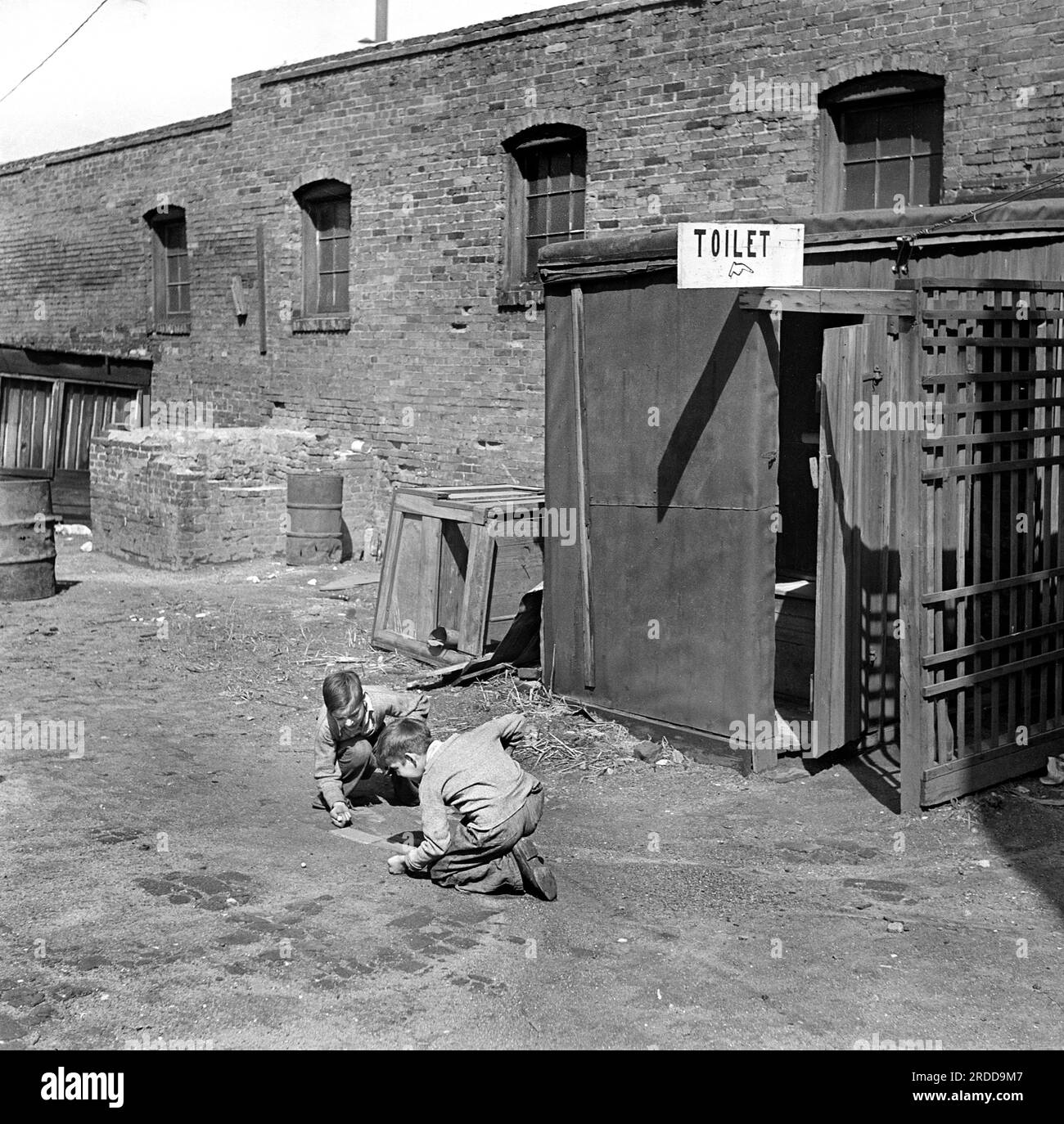 Two children playing marbles outside public toilet, St. Louis, Missouri, USA, Arthur Rothstein, U.S. Farm Security Administration, March 1936 Stock Photo