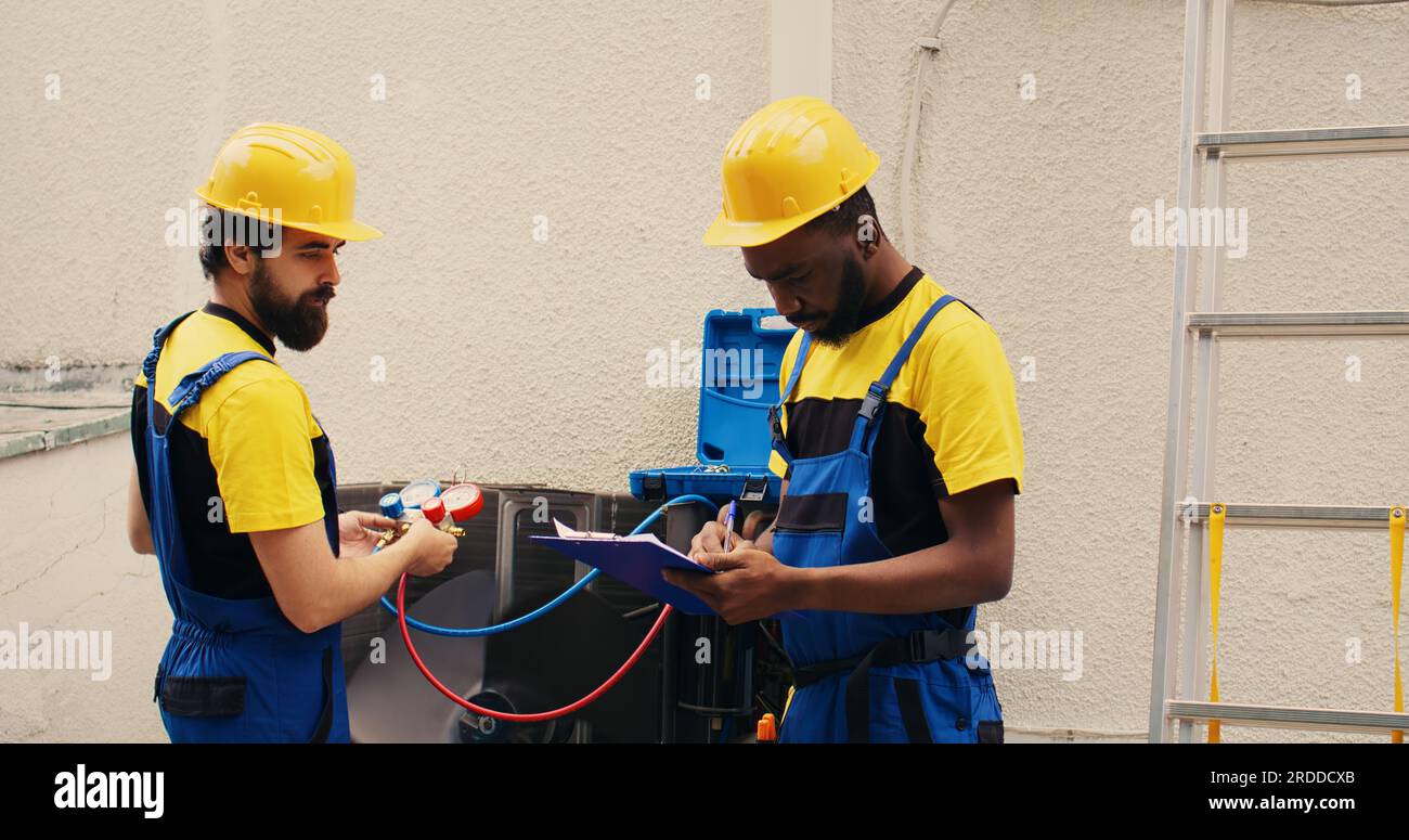 Adept repairmen working with manifold meters to check air conditioner