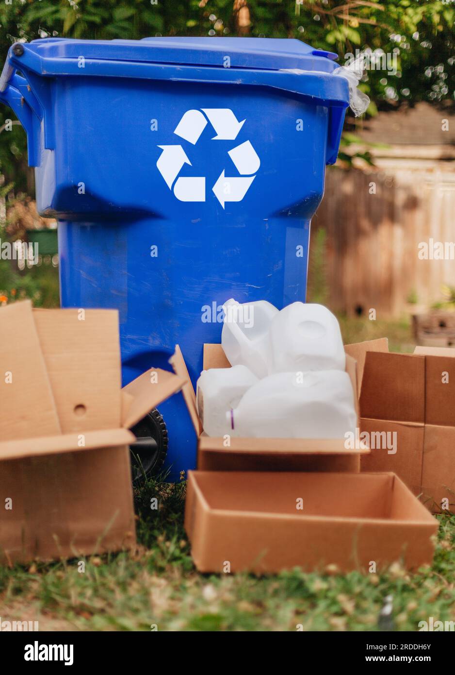 Recycling concept, pile of cardboard boxes and bottles next to recycle bin Stock Photo