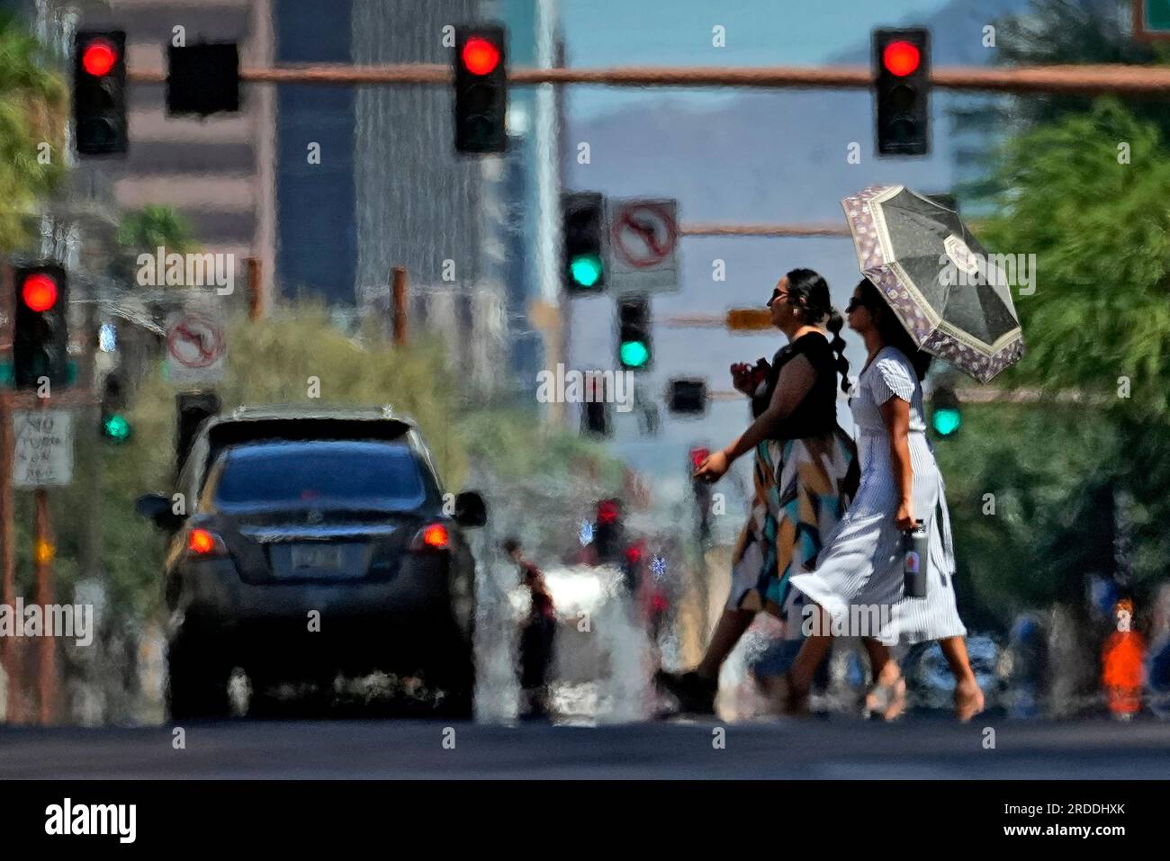 Heat ripples distort two pedestrians crossing the street on Monday ...