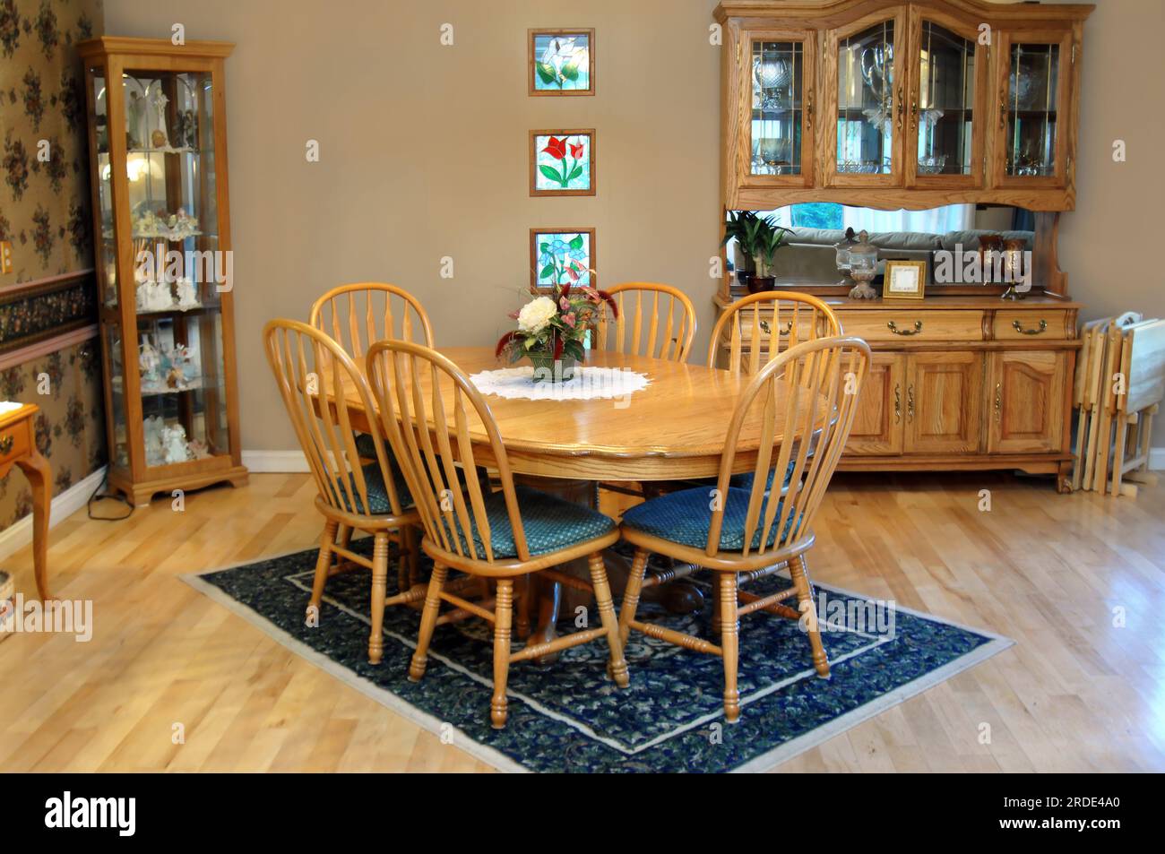 Country style dining room has oval, oak table and six chairs. Curio