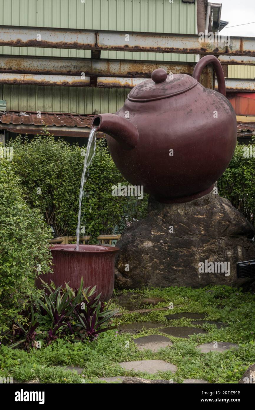 https://c8.alamy.com/comp/2RDE59B/giant-teapot-pouring-tea-into-a-large-teacup-in-pinglin-taipei-taiwan-2RDE59B.jpg