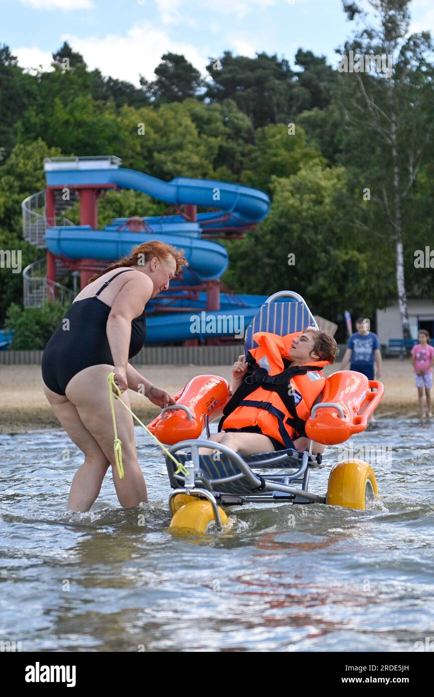 Arendsee, Germany. 12th July, 2023. Anja Reisgies (l) from the Herbert Feuchte Foundation Association pulls Emilie in a floatable wheelchair for a swim in Lake Arendsee. Credit: Klaus-Dietmar Gabbert/dpa/Alamy Live News Stock Photo